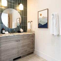 blue tile behind round mirror vanity with paintings and towels hung on wall