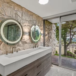 circle mirrors over vanity with rock wall behind them